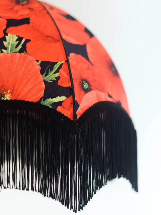 abat jour fleuri en forme de dôme avec des coquelicot rouges sur fond noir. Franges noires. Vue de profil