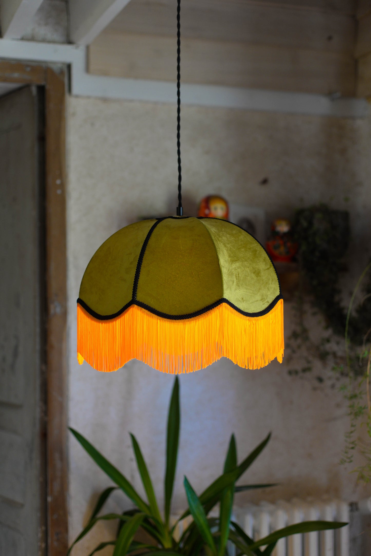 Un abat jour en suspension dome velours kaki et franges oranges. Ambiance bohème vintage