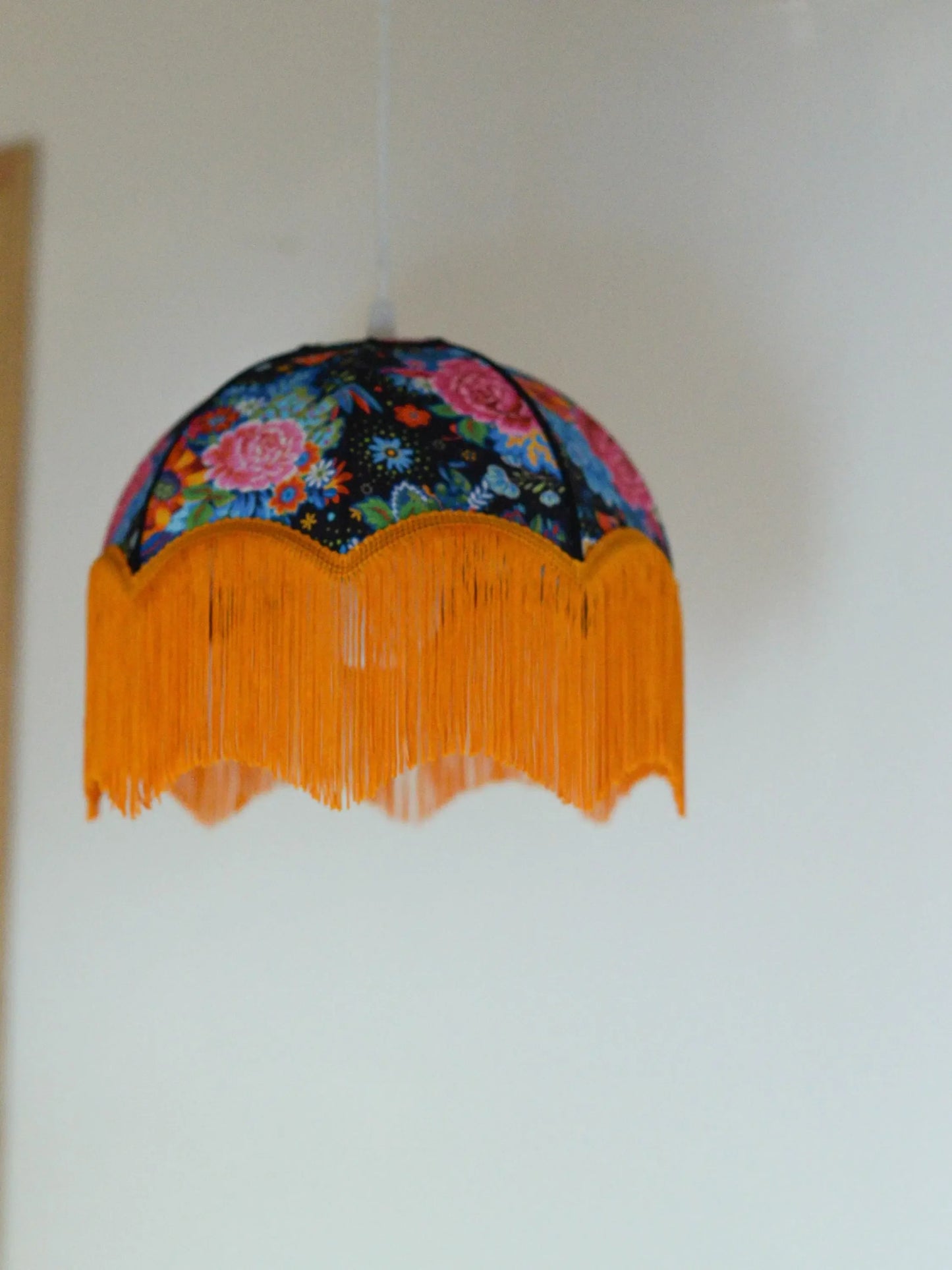 Suspension baladeuse tissu fleuri et franges oranges - Lumière à tous les Etages