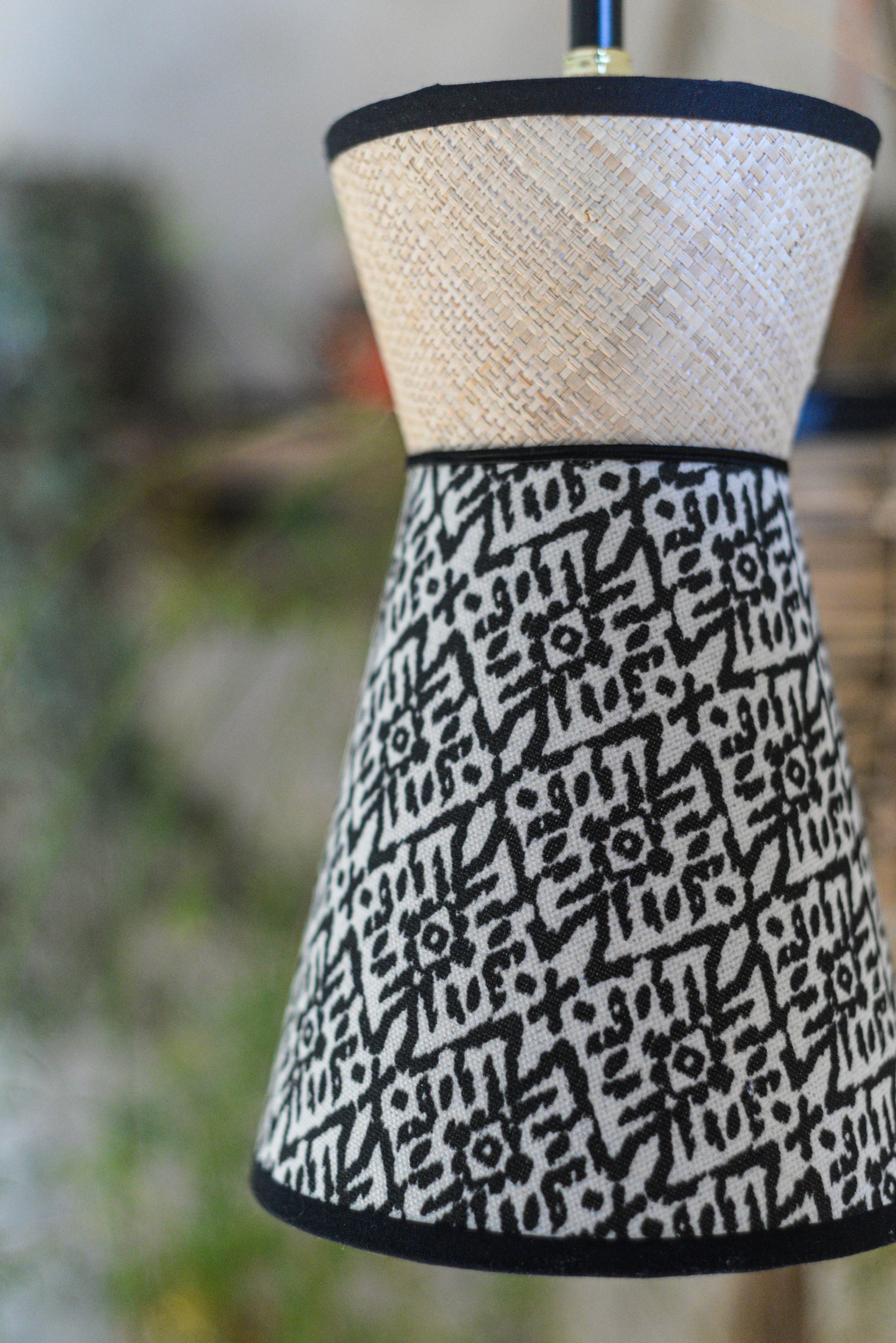 Une suspension baladeuse diabolo double cone en raphia et tissu ethnique