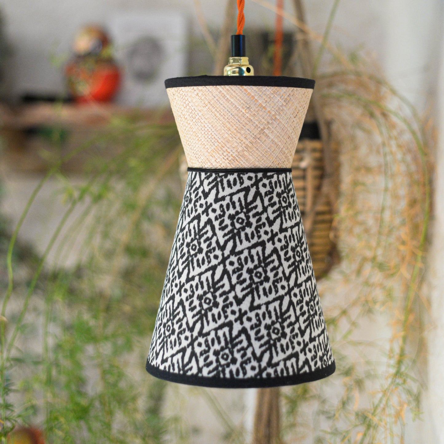 Une suspension baladeuse diabolo double cone en raphia et tissu ethnique