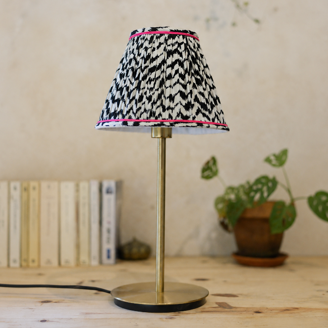 vue de face d'un abat-jour plissé noir et blanc posé sur un pied de lampe en laiton. Abat jour réalisé à la main par Lumière à tous les Etages en Bretagne