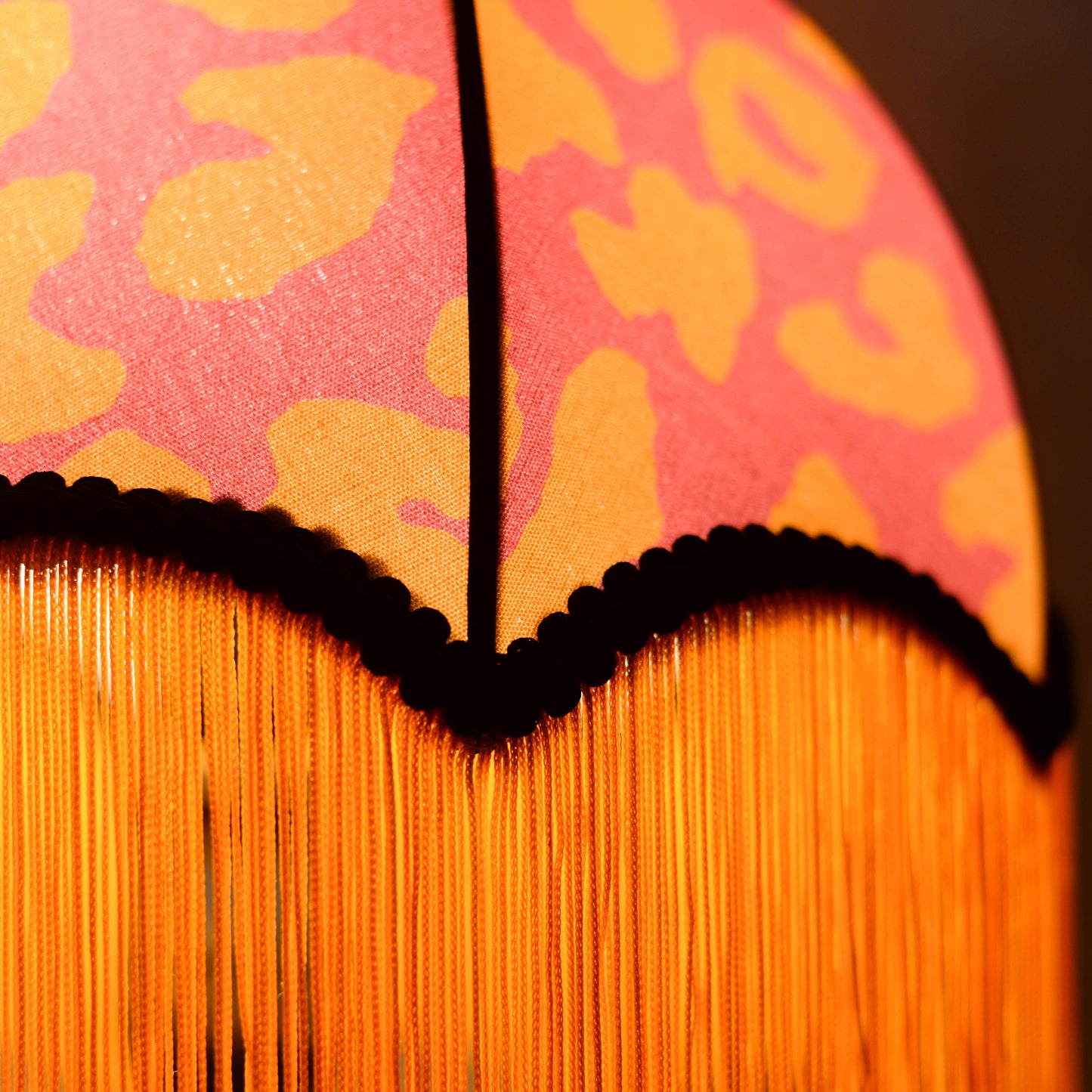 vue d'un abat jour éclairé en forme de dome tissu leopard rose et orange avec des franges