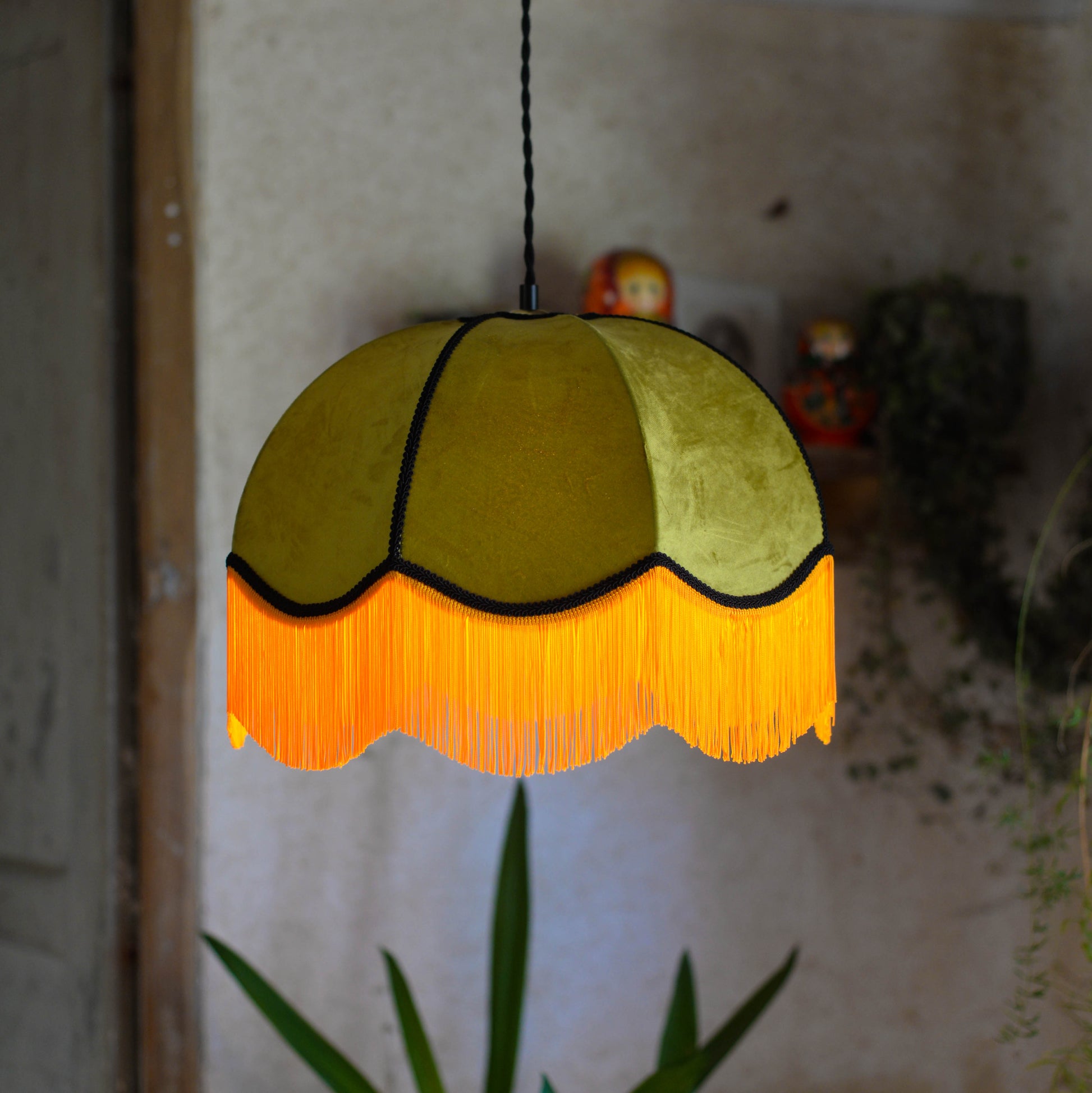 Un abat jour en suspension dome velours kaki et franges oranges. Ambiance bohème vintage