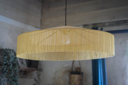 un luminaire suspension XL en raphia naturel tissé et franges beige. Réalisation unique et sur mesure réalisé par une abat-jouriste en Bretagne.