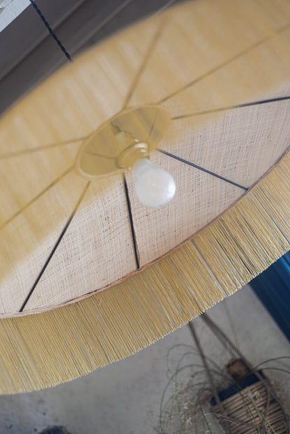 un luminaire suspension XL en raphia naturel tissé et franges beige. Réalisation unique et sur mesure réalisé par une abat-jouriste en Bretagne.