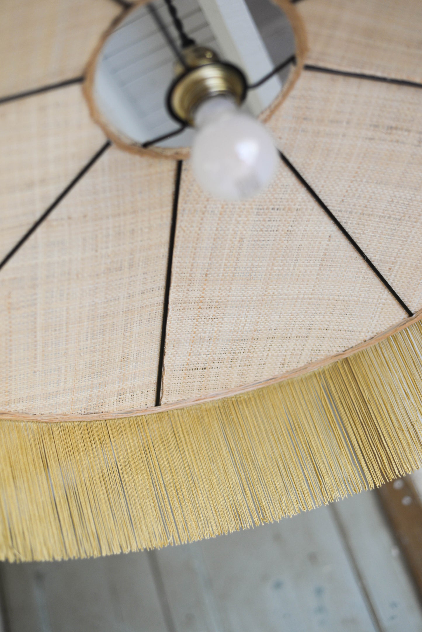 un luminaire suspension XL en raphia naturel tissé et franges beige. Réalisation unique et sur mesure réalisé par une abat-jouriste en Bretagne.