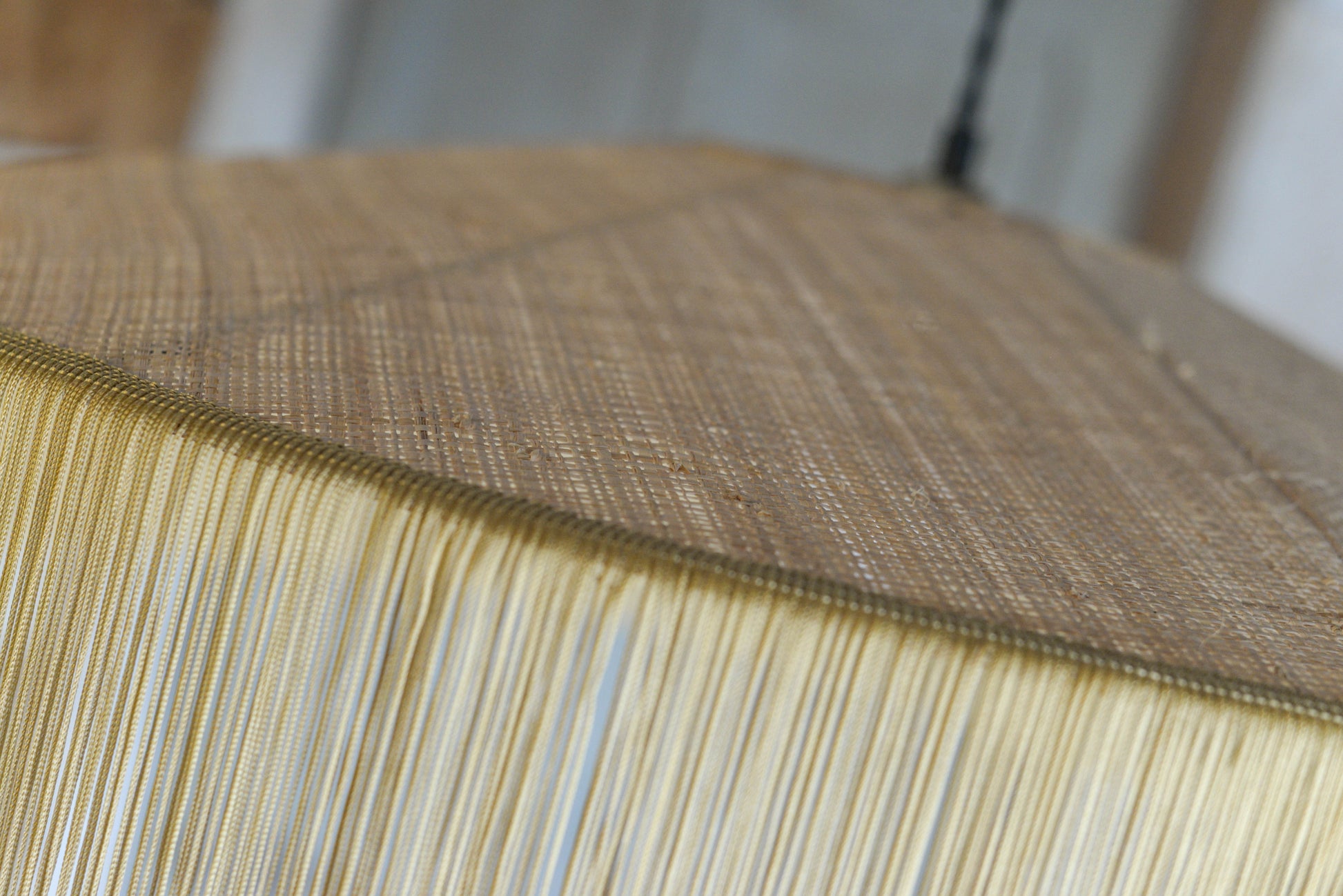 un luminaire suspension XL en raphia naturel tissé et franges beige. Réalisation unique et sur mesure réalisé par une abat-jouriste en Bretagne.