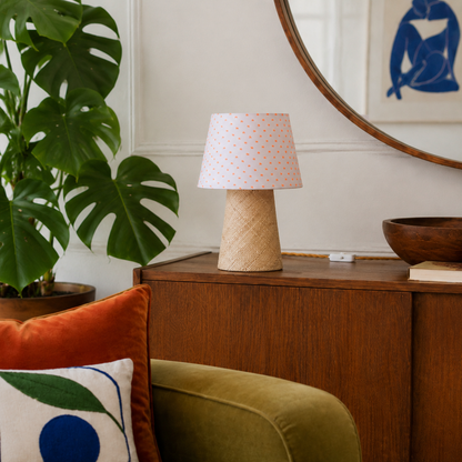 Lampe à poser Suzanne en raphia et tissu à pois orange sur une console dans un salon coloré